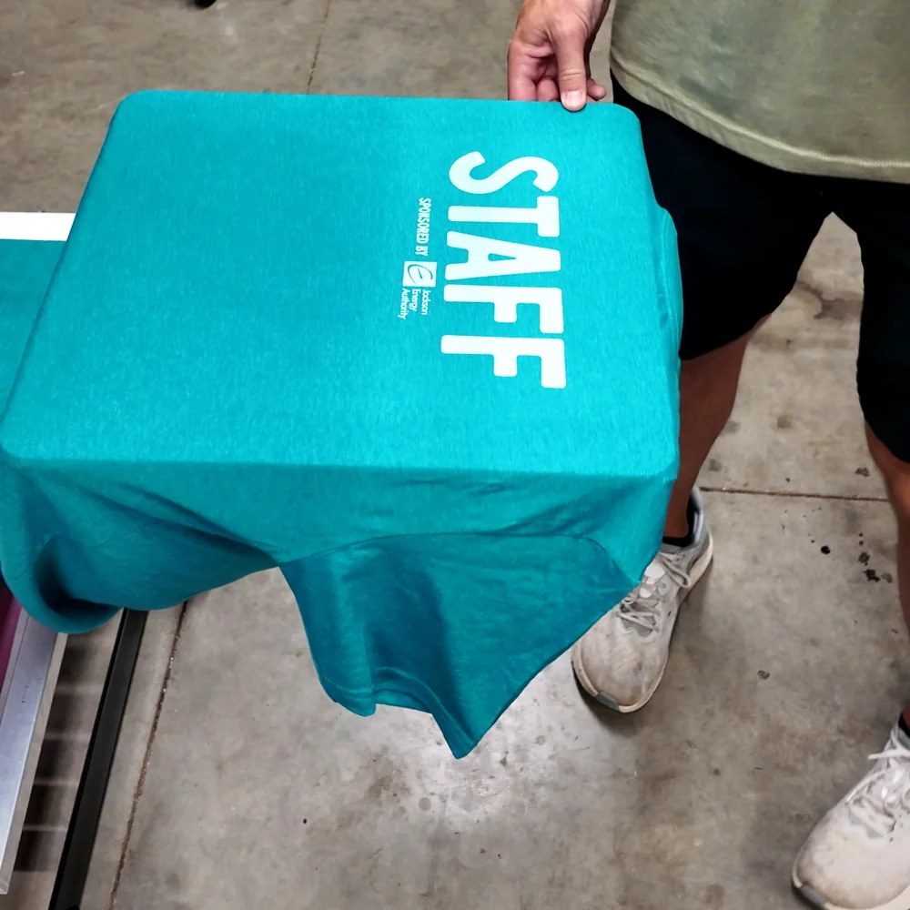 Teal First Fridays staff T-shirt printed with STAFF in white